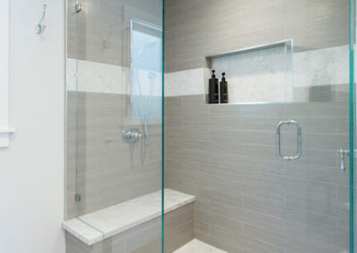 large walk in shower with gray tile and marble