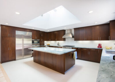 spacious kitchen with sleek dark cabinets and large skylight over the island