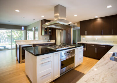 modern kitchen with mix of dark wood and white cabinets and a range hood over the island