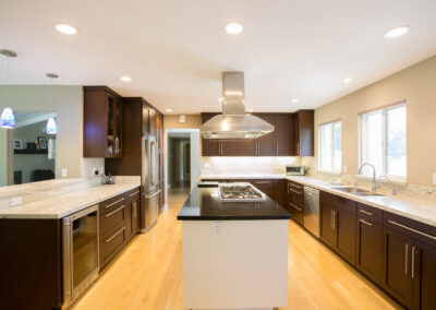 large kitchen with dark wood cabinetry and center island with range hood