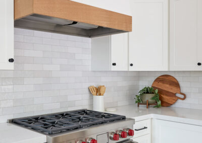 kitchen oven with range hood white cabinets and gray tile backsplash