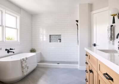 soaker bathtub with white tile shower and gray tile floors in master bathroom