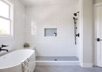 soaker tub next to large walk in shower with white tile walls and gray tile floors