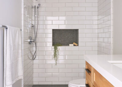 black and white geometric tile floors with white tile shower and warm wood vanity