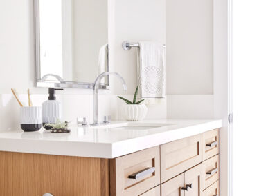 bathroom with light wood cabinetry white walls and counters