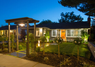 night time view of the exterior of a craftsman style house with landscape design and pergola