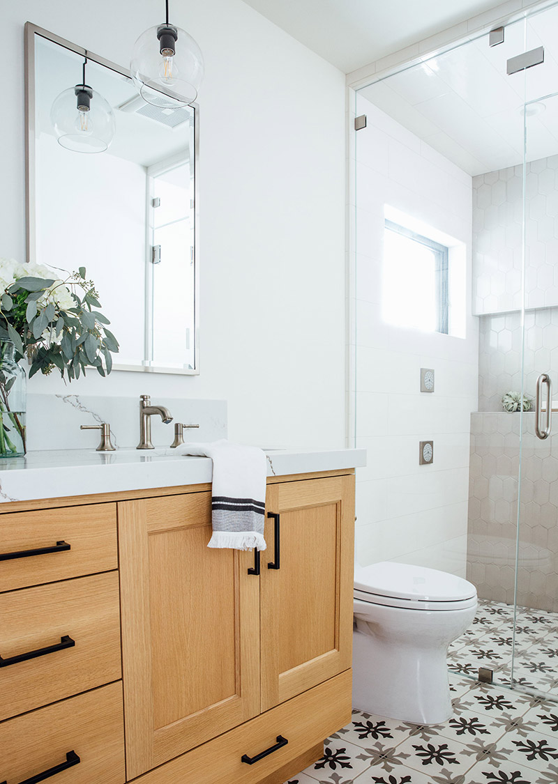 white wall bathroom with warm wood vanity cabinets and pristine tile work