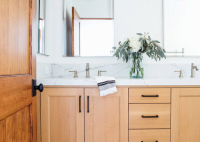 master bathroom with wood vanity and double sinks and brown and white tile floor